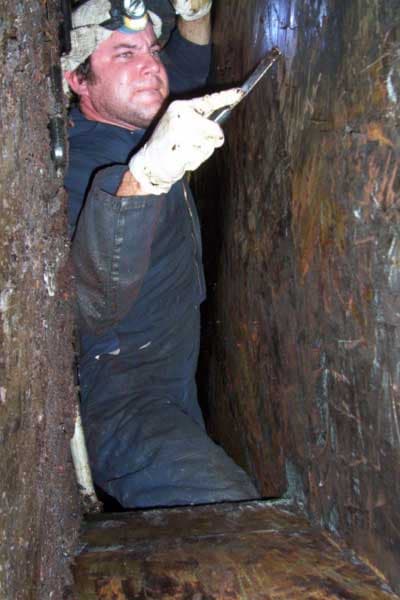 Bryan Exhaust technician hand-scraping grease from a commercial kitchen exhaust duct